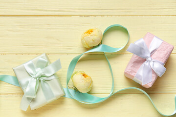 Composition with figure 8 made of ribbon, gift boxes and peony buds on yellow wooden background. International Women's Day celebration