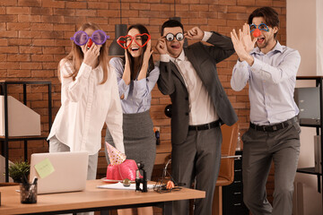 Business colleagues with funny disguise grimacing in office. April Fools' Day celebration