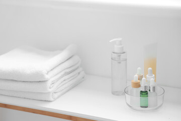 Skincare products with clean towels on table in bathroom