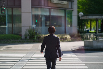 横断歩道を渡るビジネスマンの後ろ姿