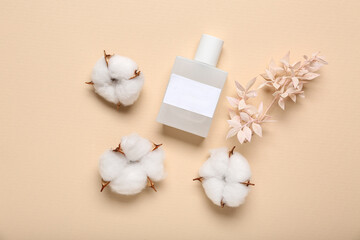 White bottle of perfume with cotton flowers on beige background. Top view