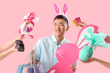 Young Asian man in bunny ears with shopping bags and paper rabbit on pink background. Easter Sale