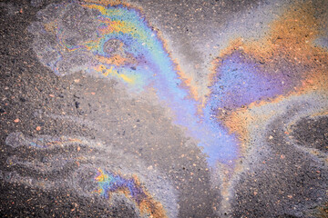 Leakage of oil or gasoline from under the car on the asphalt in the parking lot.Oil slick on the asphalt road background