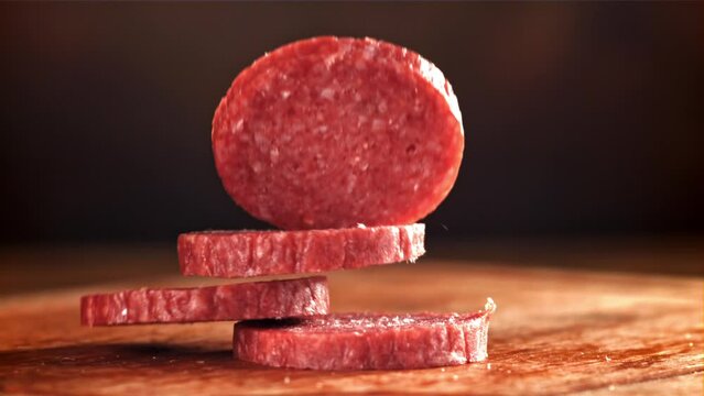 Pieces of salami fall onto a wooden board. Filmed on a high-speed camera at 1000 fps. High quality FullHD footage