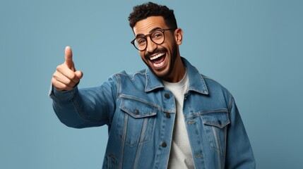Fototapeta premium A Cheerful Arab man wearing a jacket and glasses has a snowy white smile, pointing his finger sideways at copy space for your text advertisement.