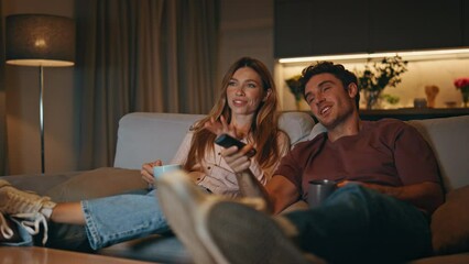 Married couple resting couch together. Smiling husband switching tv channels - Powered by Adobe