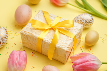 Easter gift, eggs and tulips on yellow background