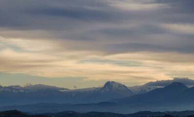 Fototapeta premium Le cime dei monti le colline e le valli immerse in una luce nebbiosa 