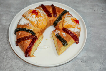 An epiphany or three kings cake (rosca de reyes) with a slice cut out and view of a baby.