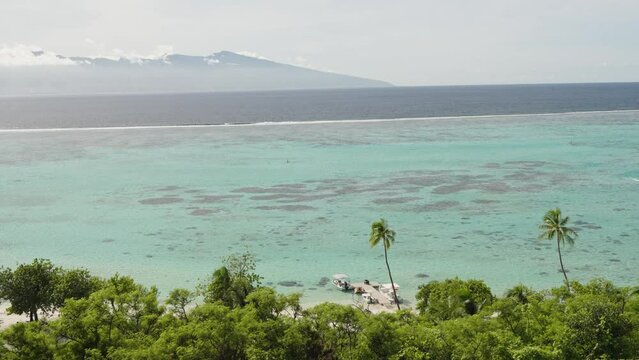 Cinematic shot of private resort boat jetty on Moorea island with Tahiti in the background