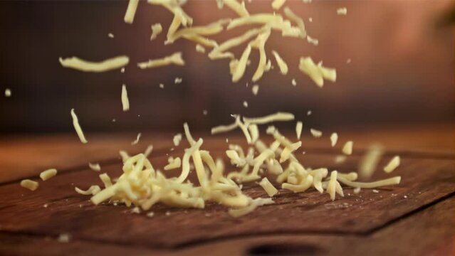 The grated cheese falls on a wooden board. Filmed on a high-speed camera at 1000 fps. High quality FullHD footage