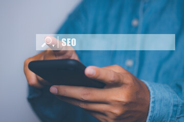 Businessman using smartphone to optimize online content with SEO tool with search bar.