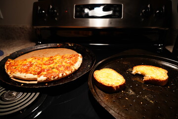 A half-eaten supreme pizza sits on a stove.