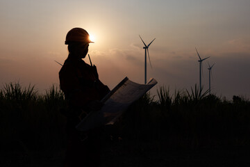 Silhouette of young female engineer holding a blueprint standing beside agricultural sugarcane and...