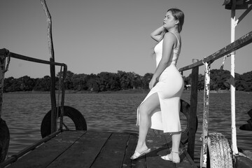 black dress, Latina with blue sky, and posing next to the lake, full body, face, posing at the dock, nice figure in black and white