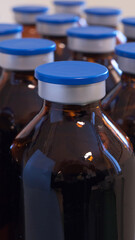 Close-up of some empty brown glass medicine bottles for injection with blue caps. Narrow depth of field