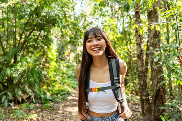 Portrait of Asian beautiful woman backpacker traveling alone in forest. 