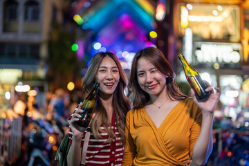 Portrait of Asian woman friends drink beer, having party infront of bar. 