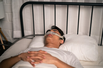 Asian man wearing cpap machine sleeping smoothly all night in bedroom. 