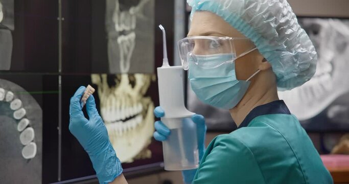 hygienist dentist doctor holds dental irrigator on teeth x-ray background