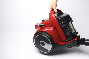 Fototapeta premium Hand holding a modern red vacuum cleaner on a white background