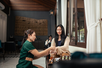 Asian Woman Spa Receptionist Assisting and present a Customer in Selecting essential oils.