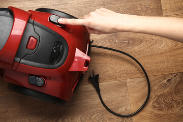 Finger presses the button of a red vacuum cleaner - obrazy, fototapety, plakaty