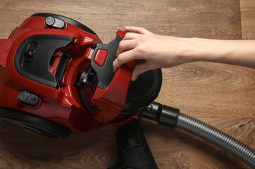 Hands hold the flask of a vacuum cleaner to collect dirt and dust on floor