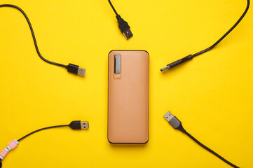 External battery power bank with usb cables on yellow background