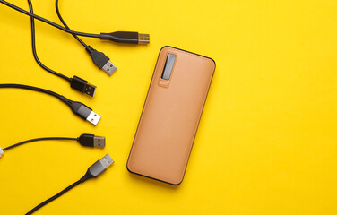 External battery power bank with usb cables on yellow background