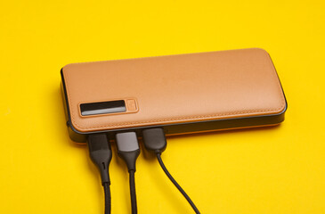 External battery power bank with usb cables on yellow background
