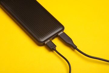 External battery power bank with usb cables on yellow background
