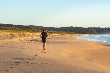 Man out for an early morning run on the beach orange sand saphire blue sea early morning light