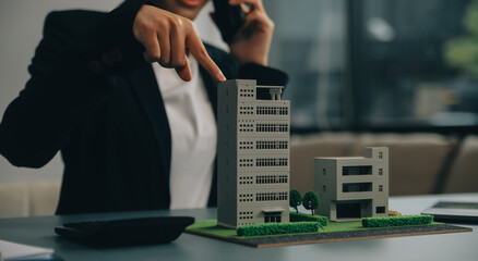 Close up realtor sit at table holds tiny house model, layout of cottage. Real estate purchase, new property, ownership, construction company make special offer to client, affordable dwelling concept