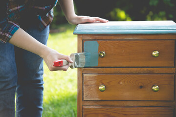 Painting a wooden furniture outdoors, an eco-friendly re-use business.