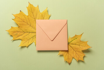 Envelope with autumn leaves on green background. Flat lay. Minimalism. Creative layout
