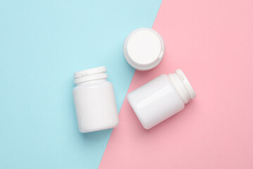 Plastic white pill bottles on pink blue background. Top view