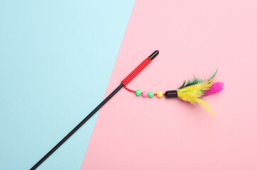 Stick with feathers on pink blue background. Cat toy