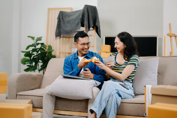 Asian young attractive couple man and woman use tablet and smartphone online shopping furniture decorate house with carton package move in new house.