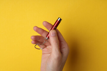 Hand holding laser pointer on yellow background