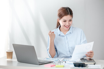 Cheerful Successful Asian Business woman using calculator and laptop for doing math finance on an...