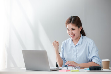 Cheerful Successful Asian Business woman using calculator and laptop for doing math finance on an office desk, tax, report, accounting, statistics, and analytical research concept 
