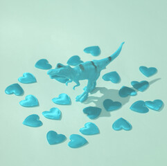 Plastic tyrannosaurus rex with hearts on blue background. Love concept, valentine's day, february...