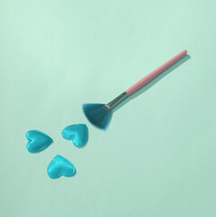 Makeup brush with hearts on blue background. Love concept, valentine's day, february 14th celebration, creative layout