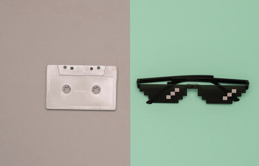 Pixelated 8 bit sunglasses with audio cassette on pastel background