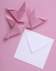 Origami carrier pigeons with a white envelope on pink background