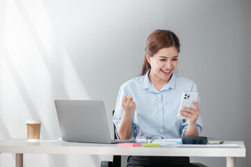 Cheerful Successful Asian Business woman using calculator and laptop for doing math finance on an office desk, tax, report, accounting, statistics, and analytical research concept 