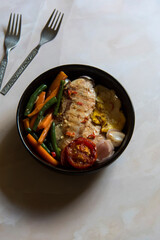 Grilled chicken fillet served with veggies in a bowl. Close up