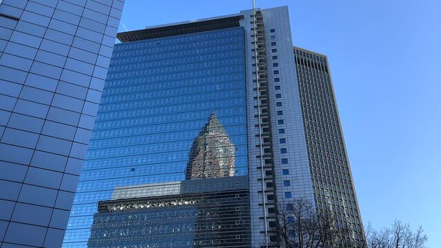 Messeturm Trade Fair Tower mirrored inside windows of Kastor Pollux Building. Frankfurt City during sunny day with blue sky. Bottom up.