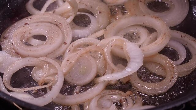 Closeup: Onion rings sizzle, sputter as they fry in hot frying pan oil